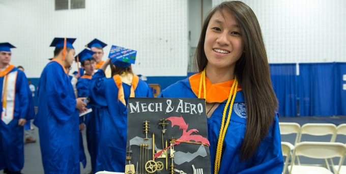 graduating student holding graduation cap with mech & aero written on it. 