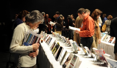 Individuals browse rows of tables displaying books. 